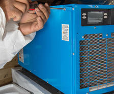 Close up of hands screwing side of dehumidifier.