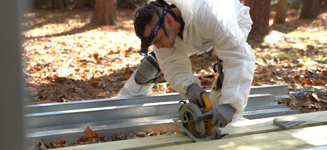 Crew cutting wooden boards and gutter guard outside.