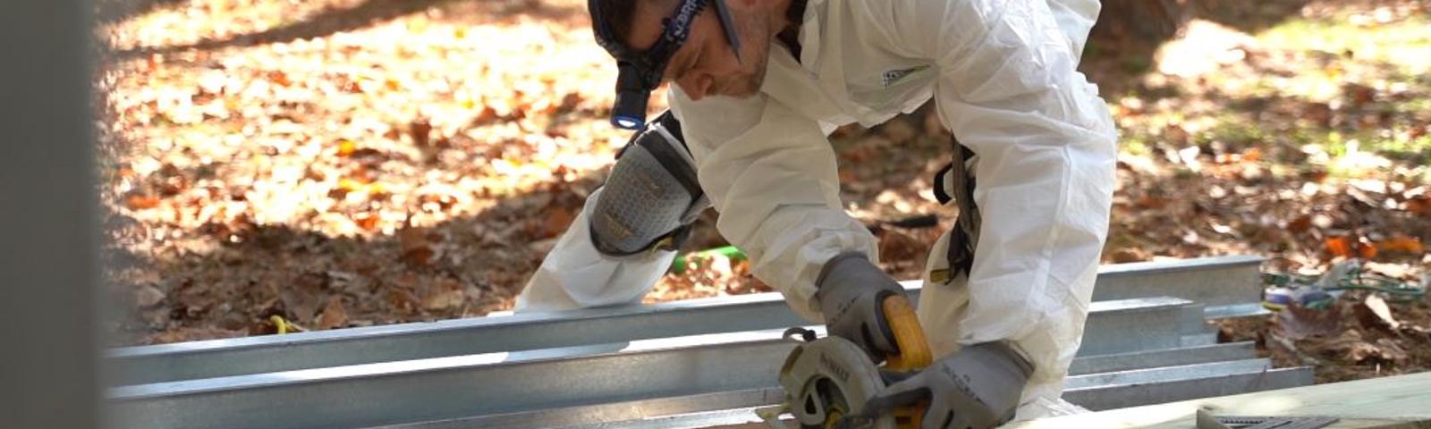 Crew cutting wooden boards and gutter guard outside.