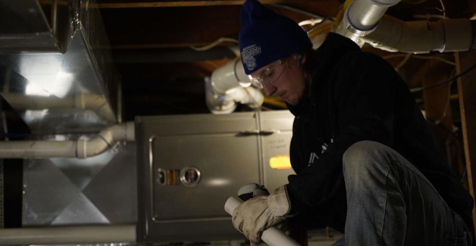 Technician installing dehumidifier in crawl space