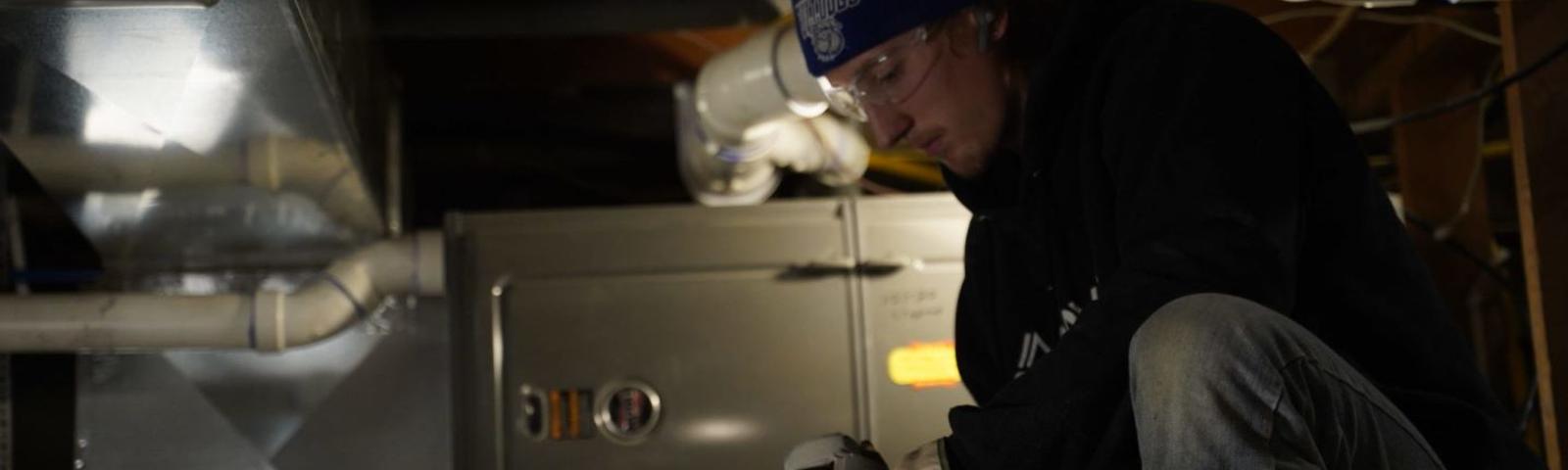 Technician installing dehumidifier in crawl space