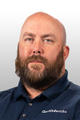 Man with a beard wearing a navy Groundworks polo shirt, posing against a light gray background.