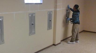Technician installing wall anchor in basement.