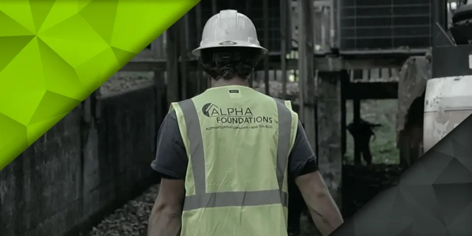 Worker in a hard hat and high-visibility vest, walking at a construction site.