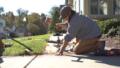 Technician leveling sidewalk and driveway.