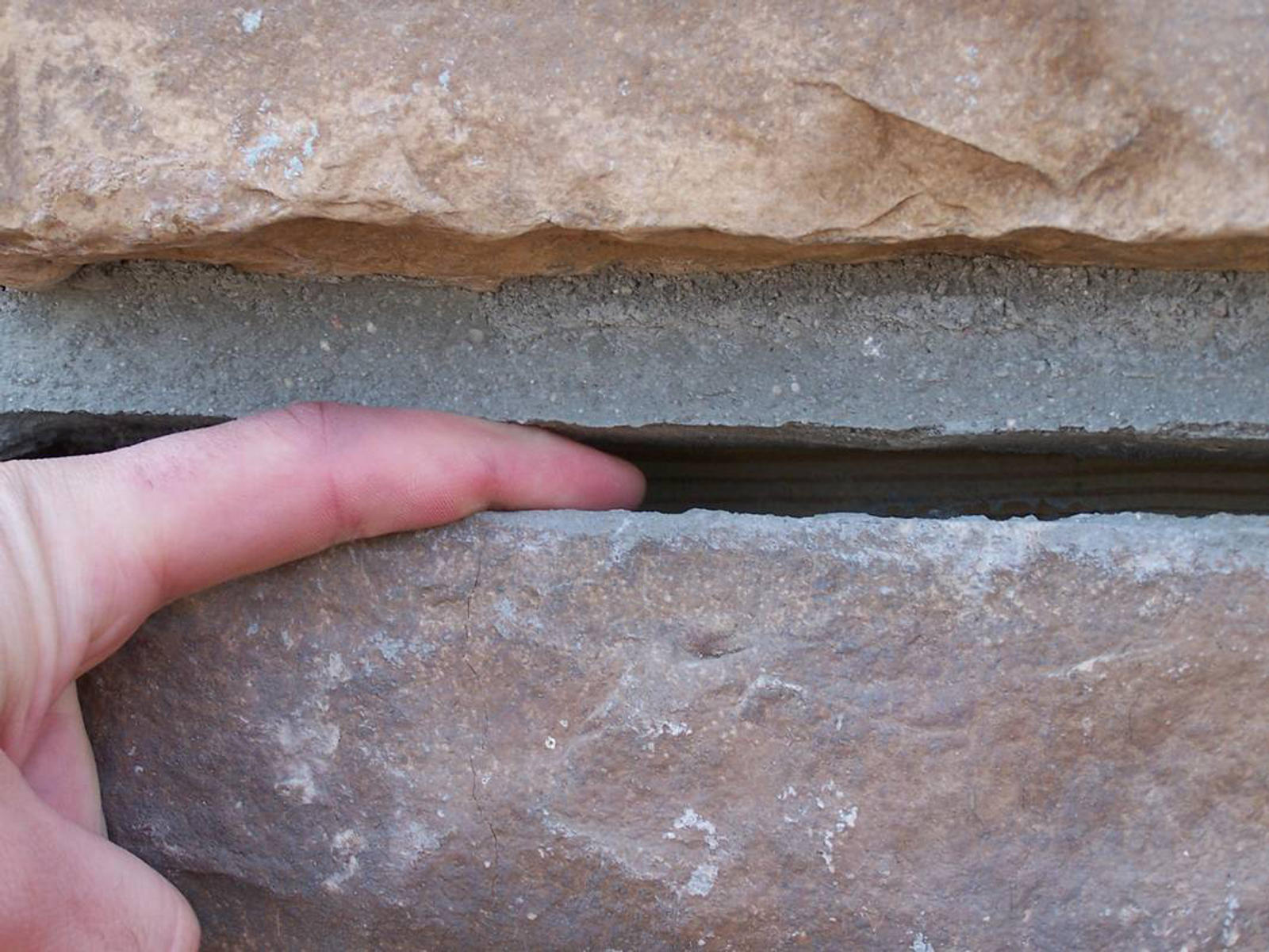 Hand in between horizontal foundation crack.