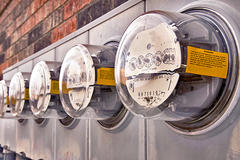 Row of utility meters with yellow tags on a brick wall, displaying numerical readings.