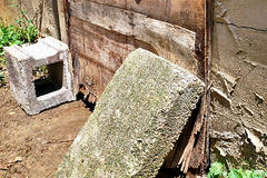 A wood rotten crawlspace door being held up by cinderblock.