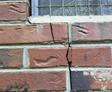 The exterior brick wall is cracking up to the window seal.