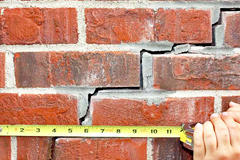 Measuring stairstep cracks in an exterior brick wall.