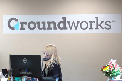 Admin staff on the phone in office with the Groundworks logo in background.