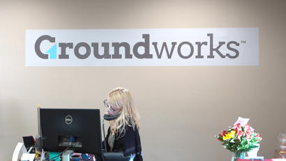 Admin staff on the phone in office with the Groundworks logo in background.