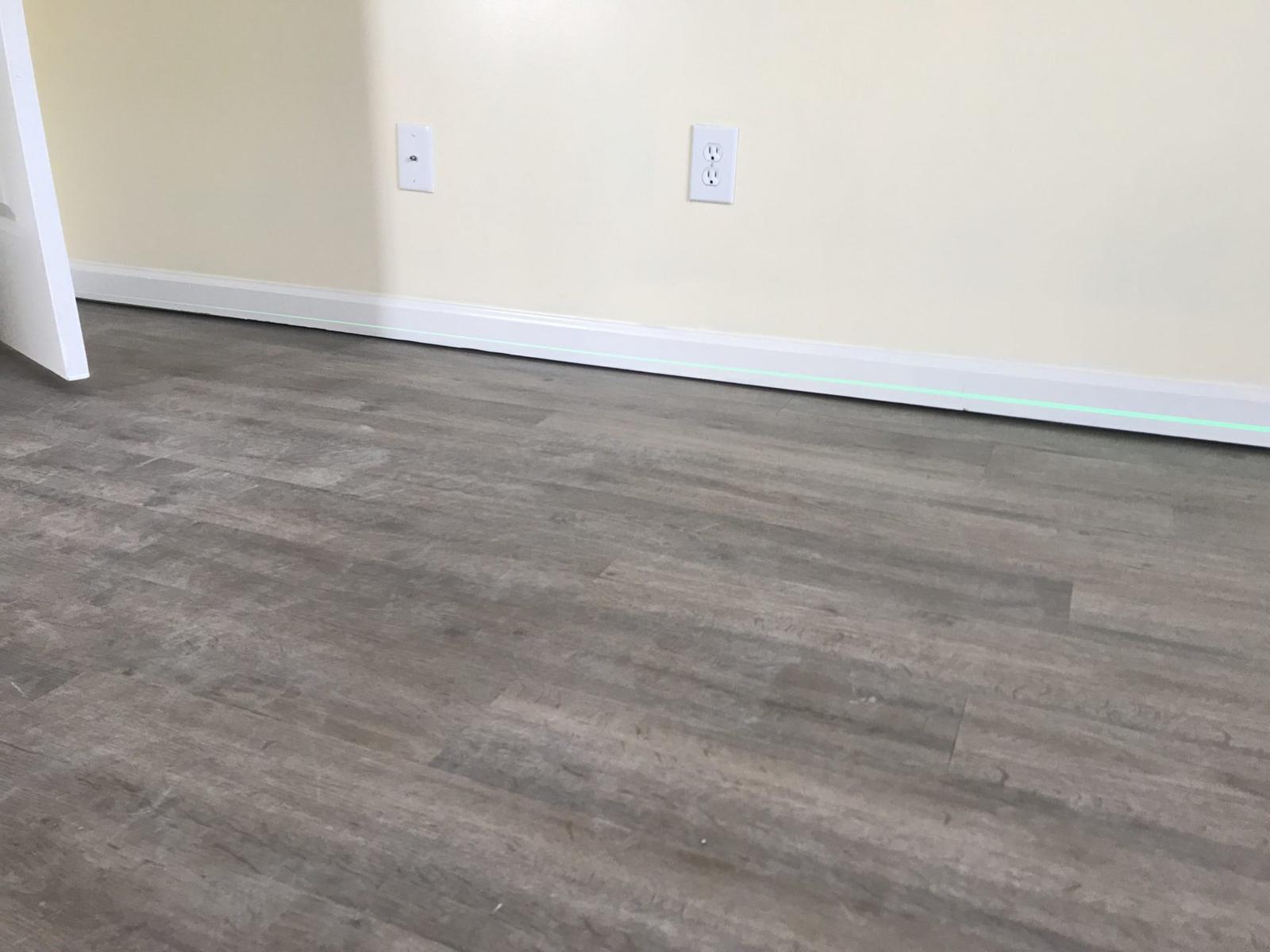 Uneven wood floors with laser level on basebaord