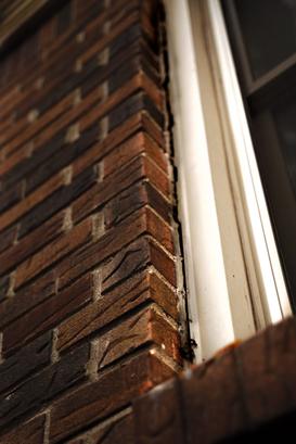 Closeup of window separating from brick