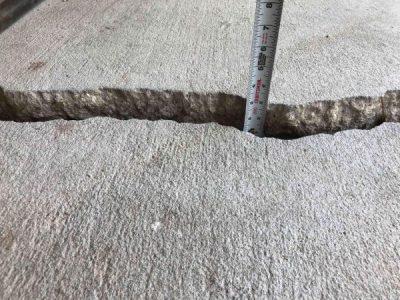 Large crack in concrete close up with tape measure