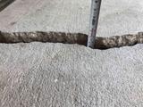 Large crack in concrete close up with tape measure