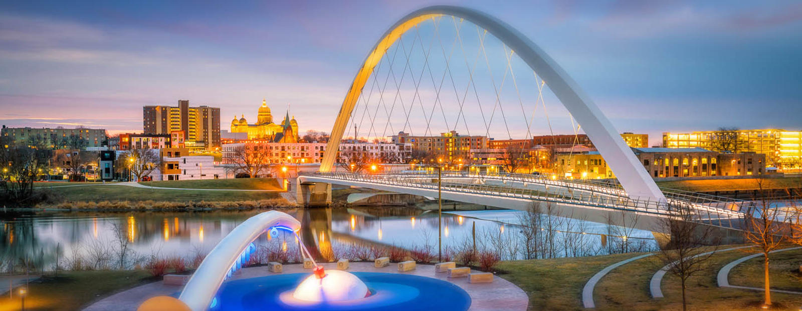 Arched bridge with Des Moines skyline at sunset