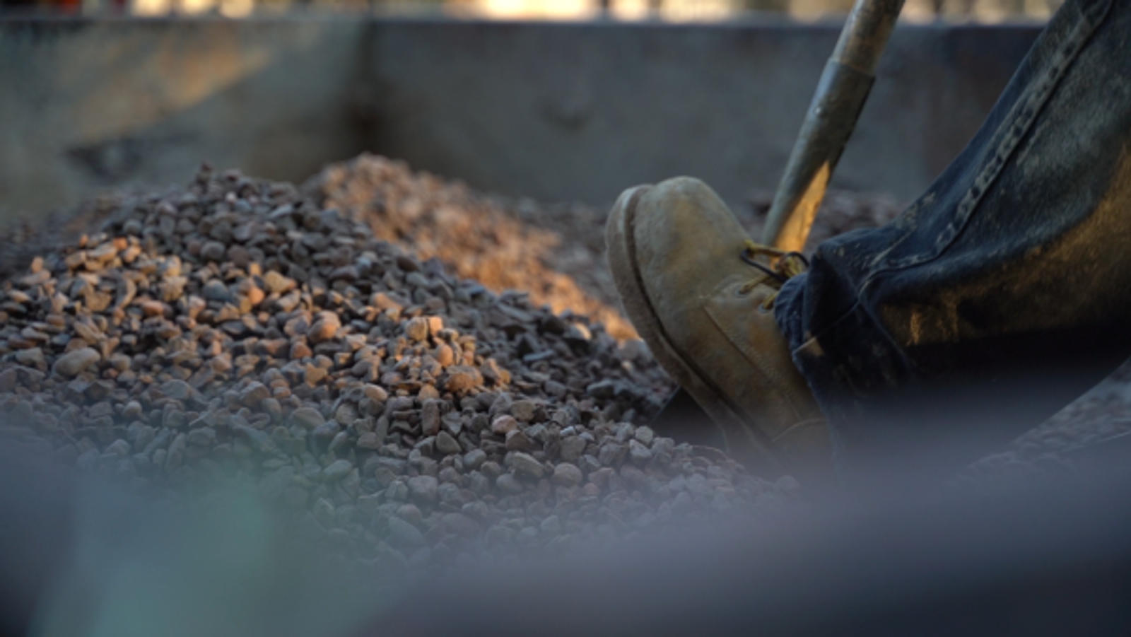 Boot pushing shovel into rocks