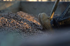 Boot pushing shovel into rocks