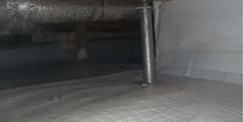 Crawl space with insulated ductwork and a metal support rod under a wooden beam.