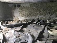 Crawl space with exposed concrete walls and plastic sheeting on the ground.