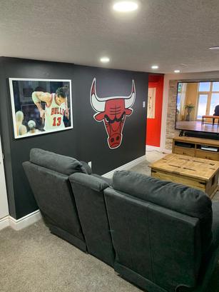 A cozy room with Chicago Bulls decor, gray sofas, a TV, and a wooden coffee table.