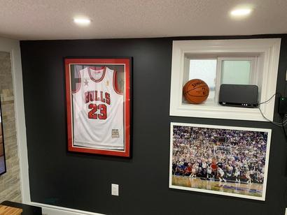 A basketball and a framed jersey on a wall