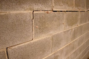 Close-up of a cracked and uneven gray cinder block wall.