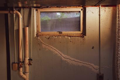 Rusty basement window with wall crack