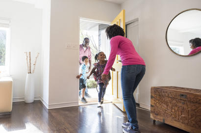 Family running into the home to mom with dad behind them - full image