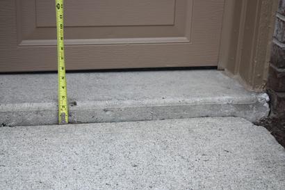 Measuring tape showing two inches of sunken driveway