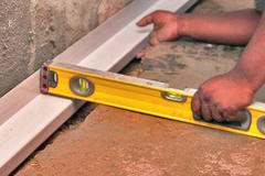 A person using a level tool to align a floor panel against a wall.