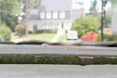 Blurred view of a suburban house and cars seen through a weathered windowsill.