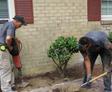 crew members working on landscaping next to a house foundation