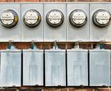 Five electrical meters on the exterior brick wall.