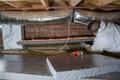 Production crew installing ExTremeBloc thermal insulation in crawl space.