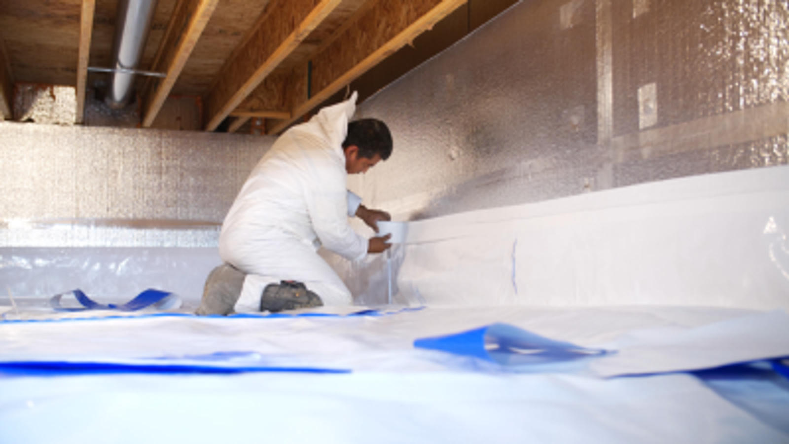 Crew installing vapor barrier wall seal.