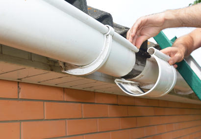 Close-up of hands installing roof gutters.