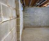 Cinder block basement wall with visible horizontal cracks and bowing, revealing a foundation problem.