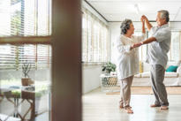 A senior couple is dancing in the living room.