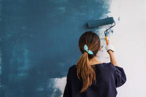 Woman painting a wall green.