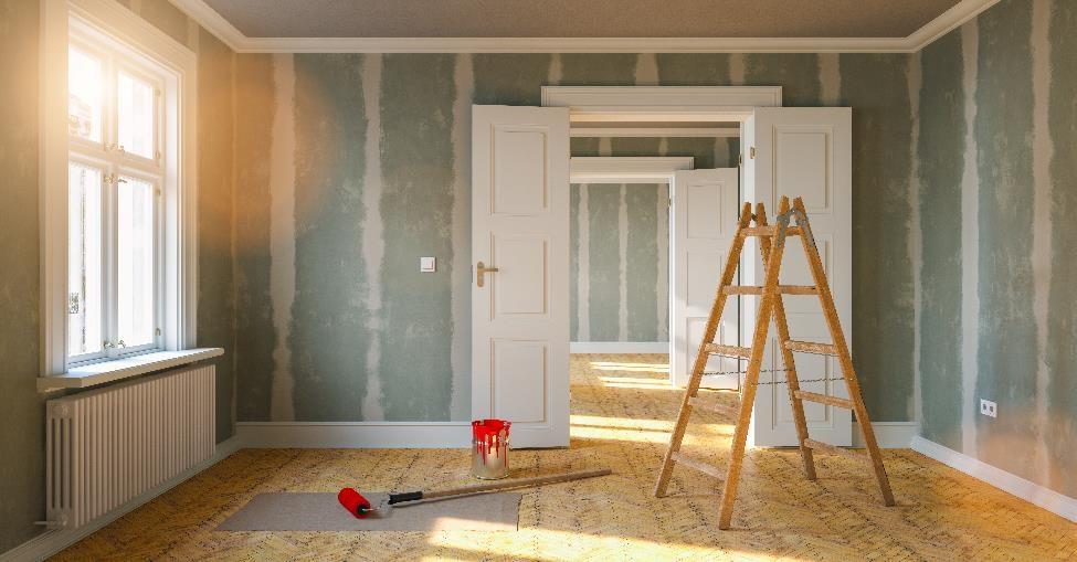 Ladder, red paint, and roller in a living room are being renovated.