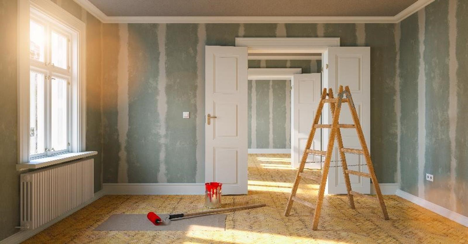Ladder, red paint, and roller in a living room are being renovated.