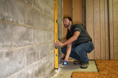 Crew measuring interior bowing wall with leveler.