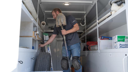 The crew in the supply truck is holding a shovel and getting supplies.