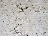 Rough, textured concrete wall surface with small holes and uneven patches.