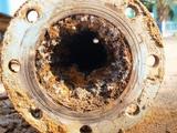 Close-up of a heavily corroded and rusted metal pipe with an open end facing the viewer.