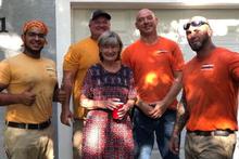OBA Crew wit homeowner, smiling in front of the residence.