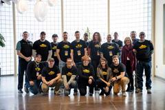 A group of people standing indoors wearing matching shirts, smiling at the camera.