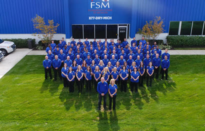 Large group of people in blue shirts standing in front of a building with "FSM" signage.